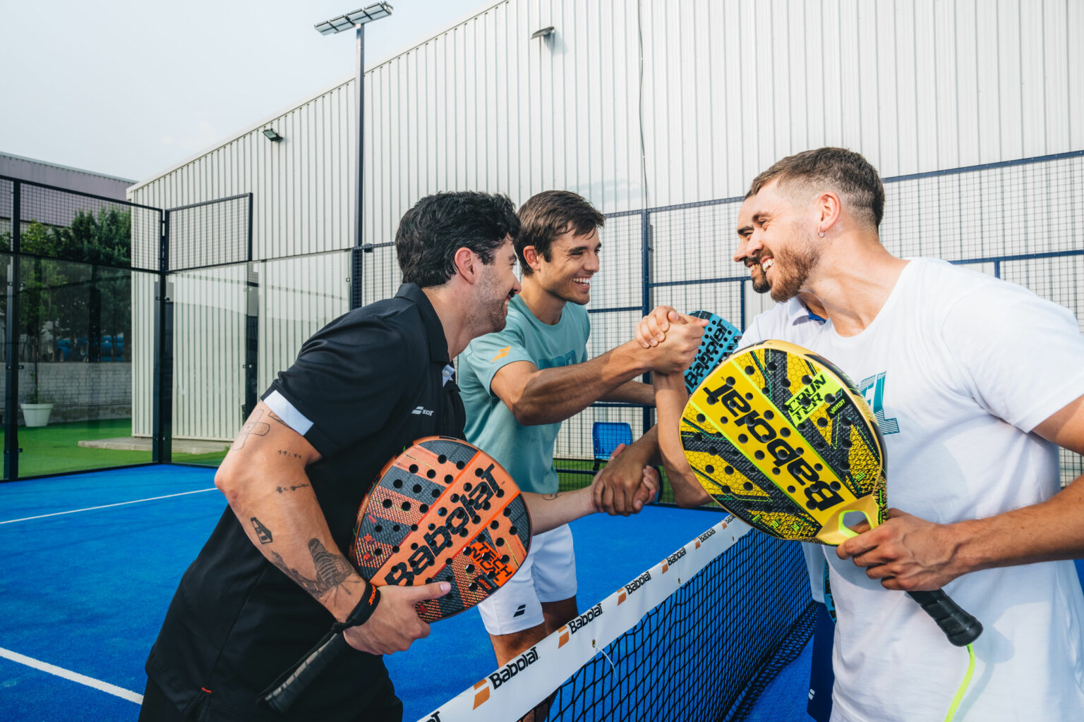Padel players shaking hands at the net after a doubles match on an outdoor Dubai court